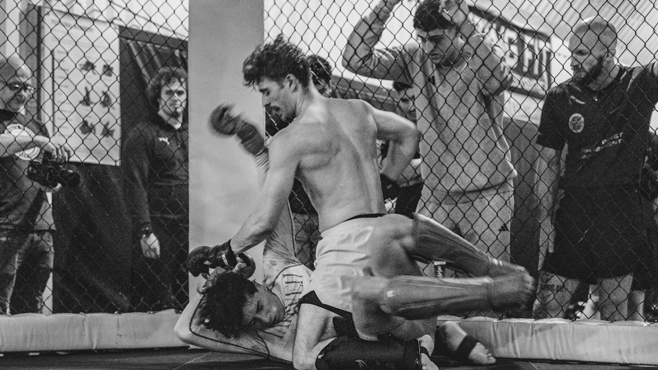 MMA fighters exchanging strikes inside a fenced cage